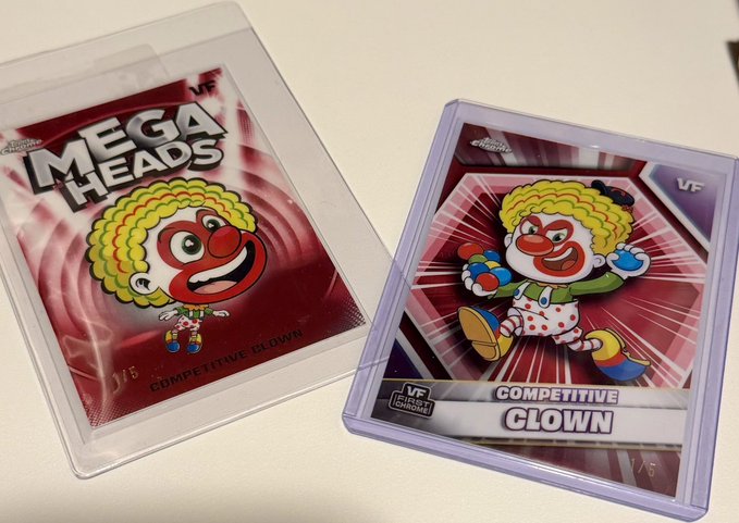 Two versions of a "MEGA HEADS" collectible featuring a "COMPETITIVE CLOWN" character are displayed, one in a clear plastic sleeve and one in a rigid plastic case.