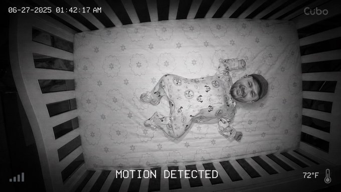 A black and white night vision baby monitor feed from Cubo showing a baby smiling in a crib, timestamped "06-27-2025 01:42:17 AM" with "MOTION DETECTED" displayed at 72°F.