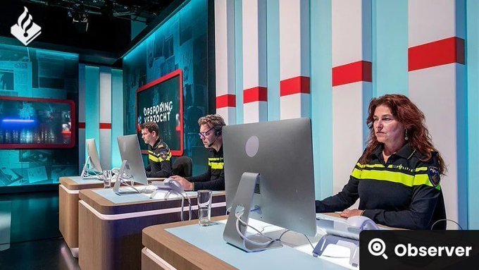 A Dutch police officer and two colleagues sit at computer workstations in a high-tech control room, with a sign reading "AANSPREEKPUNT VERZOEKEN" visible behind them, illustrating the Dutch police's investigative efforts referenced in the post about tracking down the ShinyHunters hacker who breached Odido's customer records.