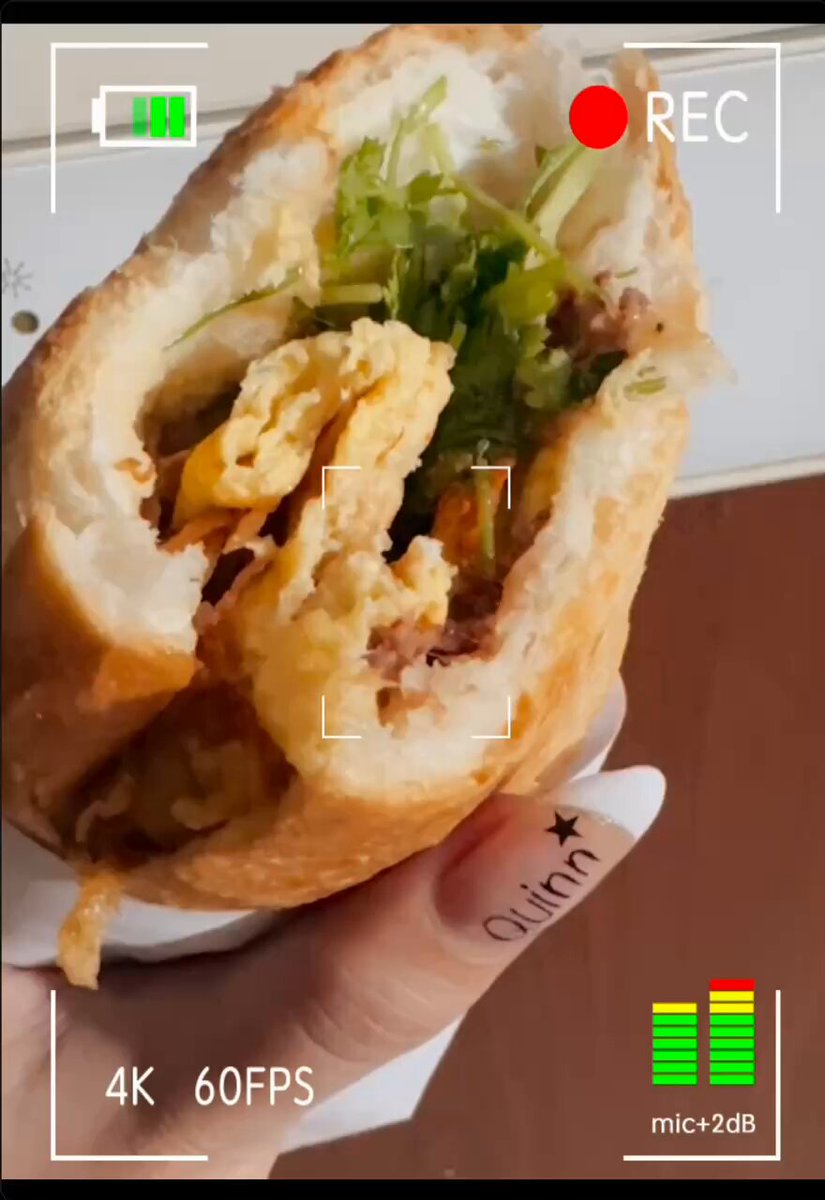 The image shows a person holding up a sandwich, which appears to be a breakfast sandwich with eggs, lettuce, and cheese. The photo has been edited to include a watermark that reads "GM CT Happy weekend @wallchain | @quipnetwork".