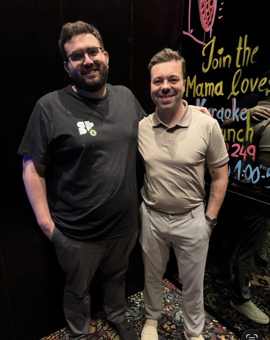 Two men posing together in front of a karaoke lounge sign that reads 'Join the Mama love Karaoke Lunch 3249 21:00'.