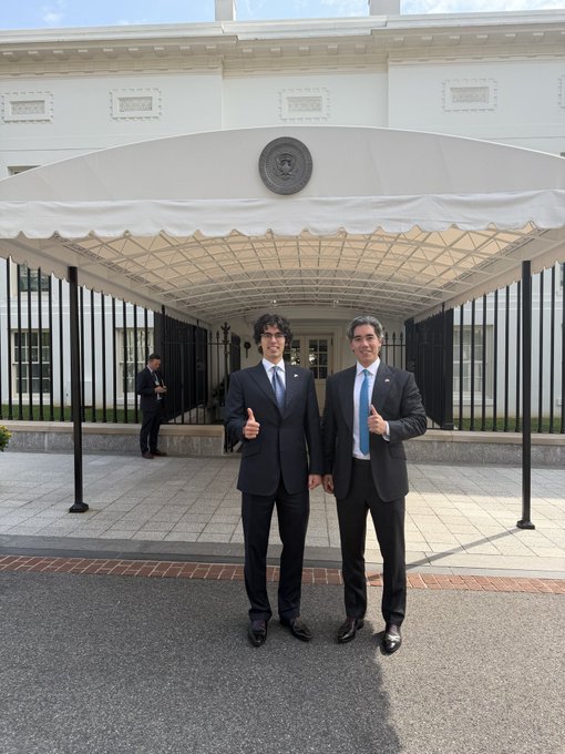 Two men in dark suits give thumbs-up gestures while standing in front of the White House portico, which features the presidential seal above its entrance. The image accompanies a post about making "crypto great again," suggesting the visit relates to cryptocurrency policy discussions at the White House.