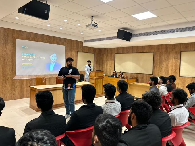 A seminar or workshop taking place in a lecture hall where a presenter is speaking in front of a slide titled 'Diving into the Future of XRP Trading with Bybit'.