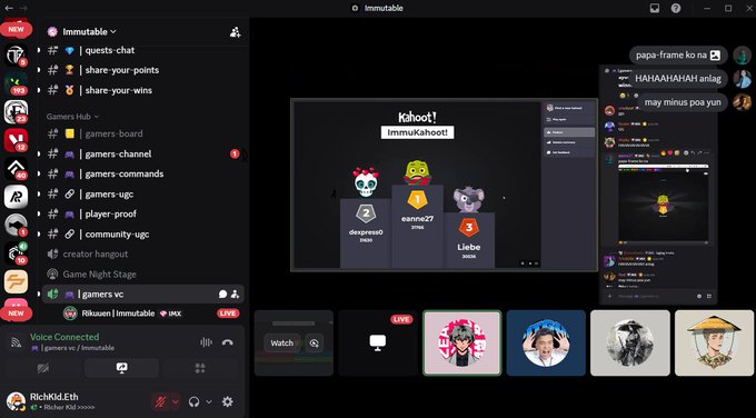 The image shows a computer screen displaying an online game called "ImmuKahoot" which has been closed for the month of May. The game is currently paused, with several players participating in the game chat room. There are multiple people visible on the screen, each engaged in different activities within the game. Some players have their avatars displayed, while others are typing messages or discussing strategies. The game appears to be a social event where participants can share ideas and interact with one another through the ImmuKahoot platform.