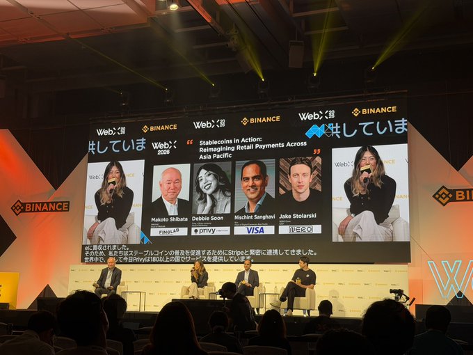 A panel discussion at a WebX 2026 event hosted by Binance, titled 'Stablecoins in Action: Reimagining Retail Payments Across Asia Pacific', featuring speakers Makoto Shibata, Debbie Soon, Nishith Sanghavi, and Jake Stolarski with Japanese subtitles displayed on the main screen.