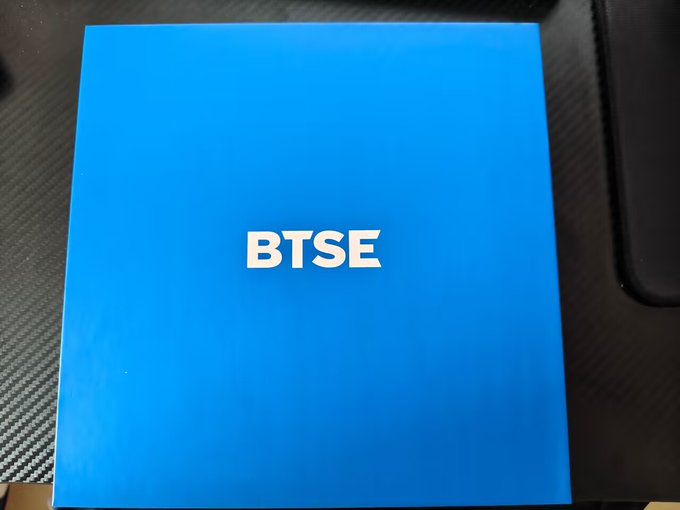 A bright blue folder or booklet with the acronym 'BTSE' printed in large white letters across the center, resting on a textured dark surface.
