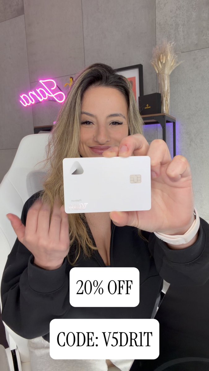 A smiling blonde woman in a black hoodie holding up a white Merit Air bank card, with overlays reading '20% OFF' and 'CODE: V5DRIT' against a backdrop featuring a pink neon sign.