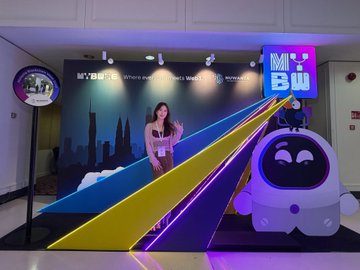 A brightly lit retail display for 'Mi BW' featuring a large purple mascot character with cat ears, a city skyline backdrop, and a poster of a woman.