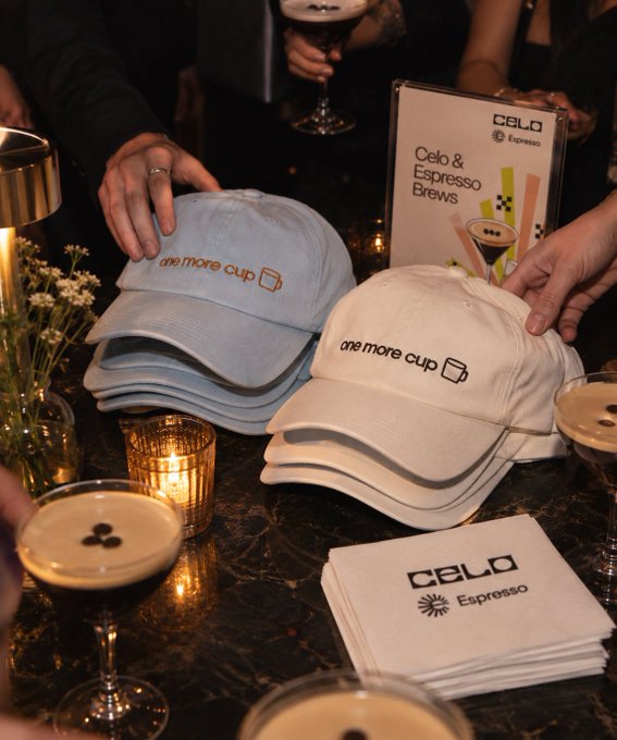 A bar scene shows stacks of light blue and white baseball caps branded 'one more cup' alongside a 'Celo & Espresso Brews' menu sign and 'Celo Espresso' branded napkins on a dark marble counter.