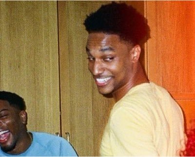 Two young men share a candid, joyful laugh together in what appears to be a locker room or closet setting, with one smiling broadly at the camera in a yellow shirt. The image humorously accompanies the post by visually representing someone confidently sharing an opinion about something (bitcoin) they clearly have no experience with, much like the amused subject cheerfully holding court despite his lack of expertise.