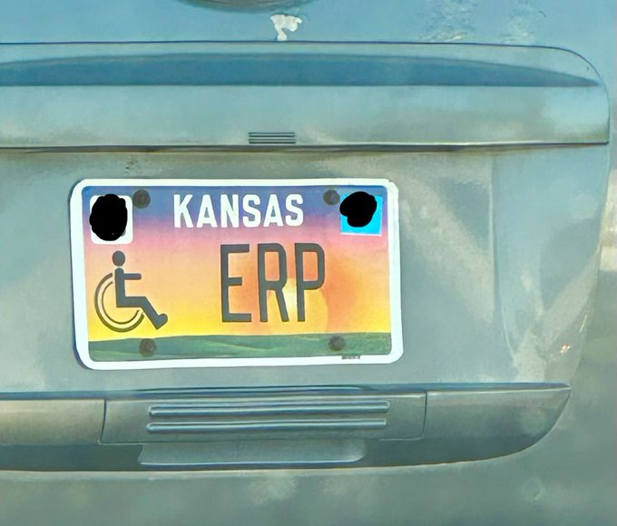 A Kansas vanity license plate reading "ERP" mounted on a vehicle, featuring a colorful sunset/sunrise design with a wheelchair accessibility symbol.