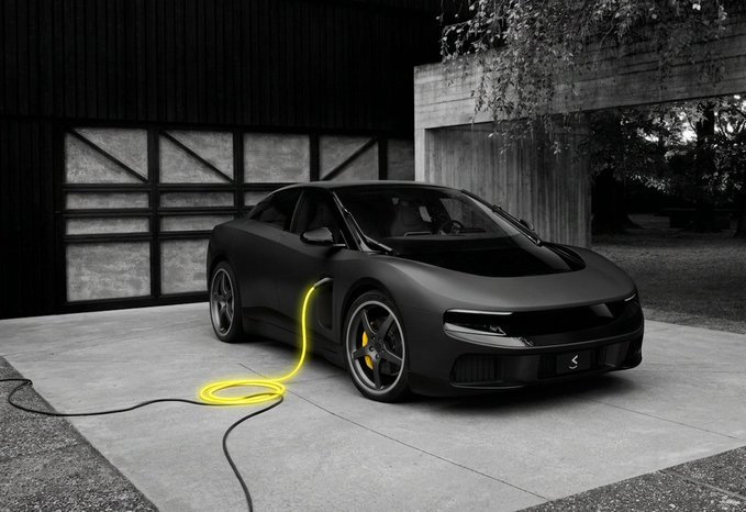 The image features a sleek black sports car with its hood open, parked next to a garage door. A yellow cord is plugged into the car's charging port, indicating that the vehicle is being charged for an electric drive system. The scene suggests that the car owner is taking advantage of modern technology and sustainable energy sources by using an electric car.