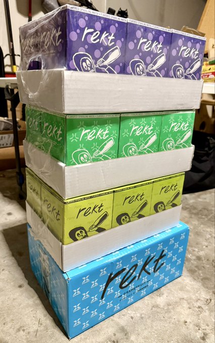 The image shows a stack of boxes with various designs and colors, including blue, green, purple, and white. The boxes are neatly arranged, possibly indicating that they have been delivered or are being prepared for delivery. One box has a label that reads "REKT", which is likely the brand name associated with these boxes. The text on the post suggests that someone has received a package from REKT World Domination, possibly containing a new item or a gift related to the company's theme.

The image also contains some text elements such as "look what arrived" and "lfg $REKT WORLD DOMINATION". These words may be part of an advertisement or promotional message for the REKT brand.