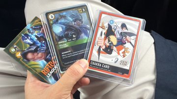 A hand holding a fanned-out collection of trading cards, including a 'CHARA CARD' featuring an anime character.