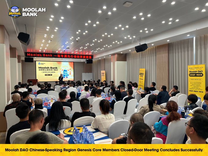 A large audience attends the Moolah DAO Chinese-Speaking Region Genesis Core Members closed-door meeting in a conference hall, with a speaker presenting at a podium beside a Moolah Bank slide and yellow Moolah DAO banners visible on stage. The image aligns with the post's announcement that the September 5–6 closed-door meeting has concluded, marking the start of the next execution phase for Moolah DAO's treasury, ecosystem, and community capital initiatives under #MoolahDAO, #BNBFi, and #GenesisCore.