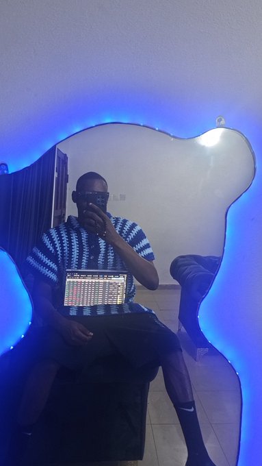 A person wearing sunglasses takes a mirror selfie while working on a laptop displaying trading or chart data, bathed in blue LED lighting that gives the scene a moody, "onchain trenches" atmosphere—visually reinforcing the post's theme of being indoor and deeply active in crypto trading/monitoring.