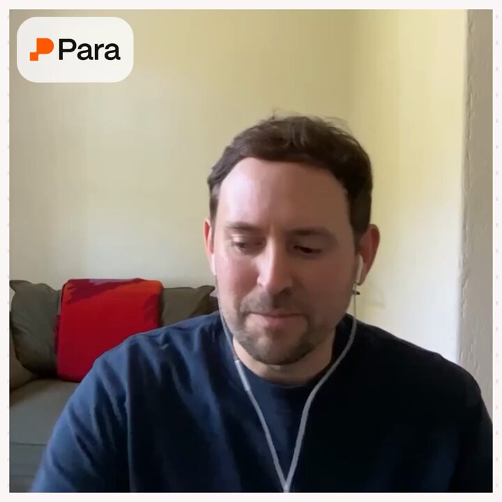 The image features a man wearing a blue shirt sitting at a desk with headphones on his ears. The man appears to be focused on something or someone outside of the frame. There are two couches visible in the background, one located behind the man and another further back. Additionally, there is text that reads "Para" and "@stablecoin_xyz", which could potentially be related to a discussion about stablecoins or a specific project involving stablecoins.