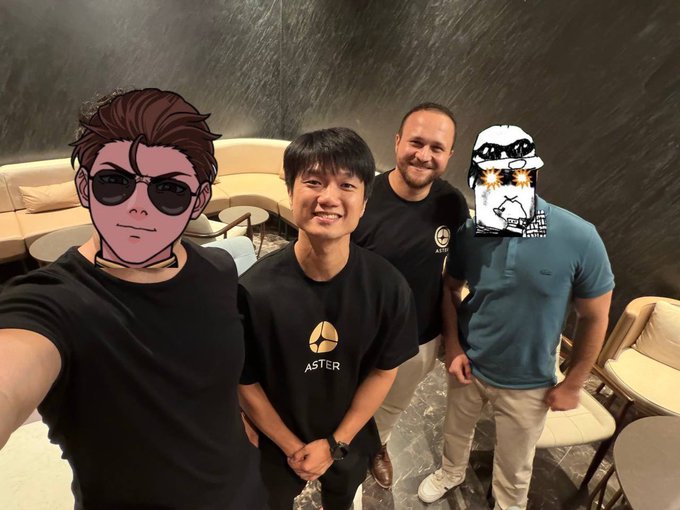 The image features a group of three men posing for a photo, each wearing a different colored shirt - black, blue, and white. The man in the center stands out as he has his face partially obscured by a mask or a drawing on his head. The other two men are standing next to him, with one of them holding a drink in their hand. The background includes chairs and a couch, suggesting that they might be at an event or gathering.
