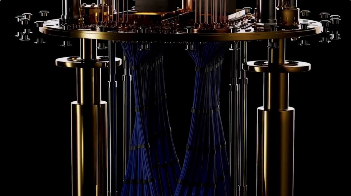 The image depicts a large, metallic structure with blue wires hanging down from a central pedestal. The text in the image suggests that the development of the first quantum computer has been delayed due to technical challenges or delays.