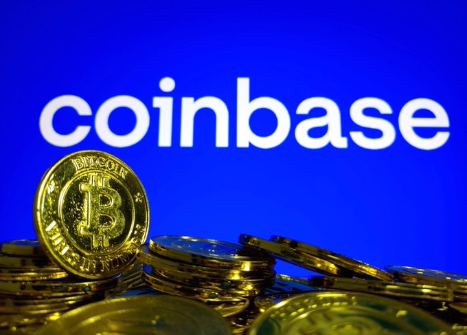 A stack of gold Bitcoin tokens sits in the foreground against a blue background displaying the white "coinbase" logo.