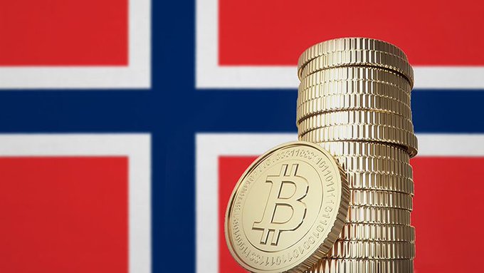 A stack of gold Bitcoin coins in the foreground with the Norwegian flag displayed in the background.