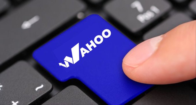 A finger presses a blue key on a black keyboard labeled with the 'YAHOO' logo in white.