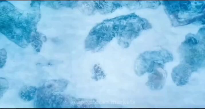 The image shows a close-up view of a white surface with blue spots, possibly resembling snow or ice crystals. The background appears to be a light brown color, which contrasts with the white surface. There are no texts or other objects present in the image.