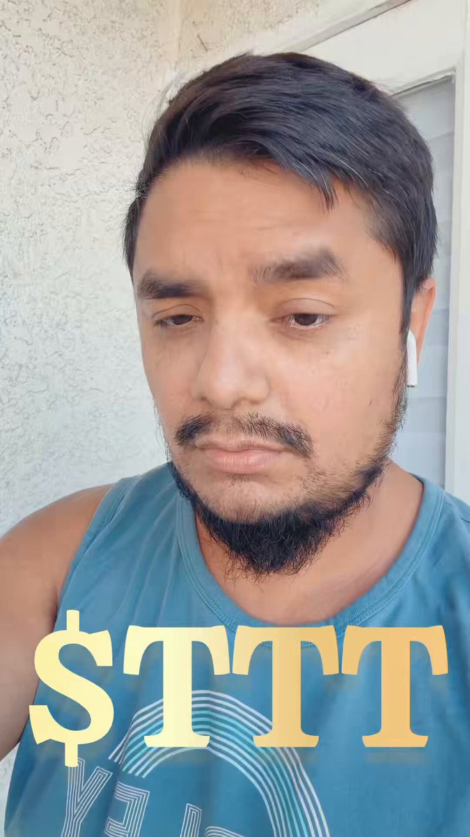 The image features a man with a beard wearing a blue tank top, who appears to be looking down at his phone screen. The caption of the photo reads "Sttt" written below the man's face.