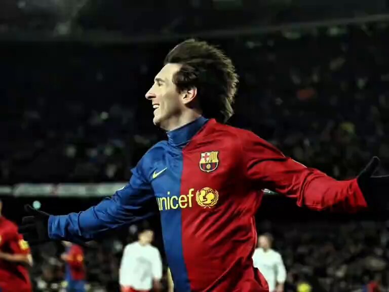 The image features a soccer player wearing a red and blue jersey with the word "Barcelona" written on it. The player appears to be celebrating or reacting to something, possibly related to their team's performance. There are several other people present in the scene, but they are not the main focus of the image.