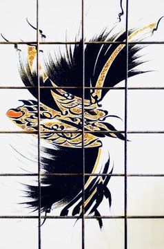 A stylized artwork of a black and gold bird with flowing feathers, displayed across a grid of white tiles.