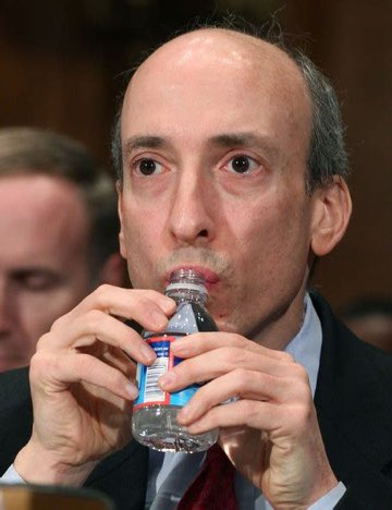 A close-up photograph of a balding man in a suit drinking from a small water bottle during what appears to be a congressional hearing.