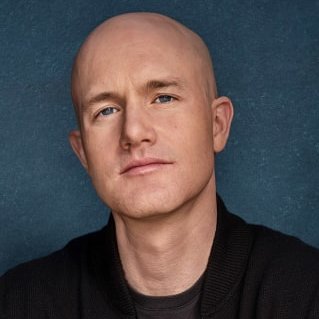 A bald man in a dark sweater poses against a blue backdrop; the image accompanies news of Coinbase's legal victory over the SEC.