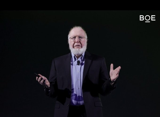An older man with a white beard, wearing a dark blazer and light shirt, gesturing while presenting on stage with the 'BOE' logo in the upper right corner.