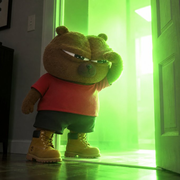 A small, grumpy-looking brown bear plush toy in a red shirt and Timberland boots stands in a doorway blocking an intense green glow, humorously representing the sudden, overwhelming bullish surge referenced in the post about $BOBO's bull market activation.