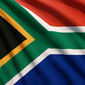 The image shows the South African flag, featuring its distinctive design with a green Y-shape outlined in white and yellow, a black triangle at the hoist, and red and blue horizontal bands. The flag visually represents South Africa, the country referenced in the accompanying news post about new proposed reporting rules for crypto transfers to offshore platforms and self-custody wallets.
