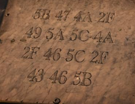 A close-up photo of a stone or metal surface engraved with several rows of alphanumeric coordinates, including '5B 47 4A 2F', '49 5A 5C 4A', and '43 46 5B'.