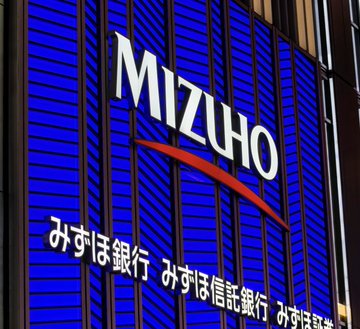 A blue illuminated sign displaying the 'MIZUHO' logo and the Japanese text 'みずほ銀行 みずほ信託銀行 みずほ証券' (Mizuho Bank, Mizuho Trust & Banking, Mizuho Securities).