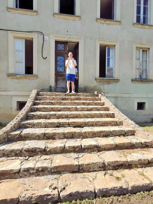 A man stands at the top of weathered stone steps in front of an aged building, visually echoing the post's theme of focusing time on meaningful, real-world pursuits like building a real estate portfolio rather than chasing crypto tokens like $ANSEM.