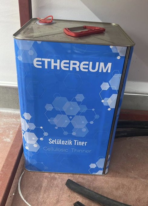 A blue metal can labeled 'ETHEREUM Selülozik Tiner (Cellulosic Thinner)' with a red plastic handle, sitting on a floor.