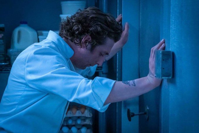 A man in a light blue shirt leans his head against a door in a moment of visible distress, bathed in cool blue lighting. The image visually echoes the post's sentiment of feeling trapped and helpless, as the man's posture—head down, hands pressed against the door—mirrors the despair of being stuck in a losing crypto position with no rescue in sight.