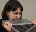 A young woman with dark hair leans in close to look at a laptop screen, appearing curious or focused on the content. The caption "This is who runs this account" suggests she is identifying herself as the person behind the account or content being shared.