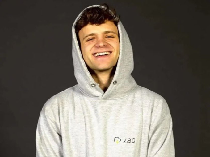 A young man in a gray "zap" hoodie smiles broadly while wearing the hood up against a dark background. The image pairs with the quote about Jack Mallers predicting Bitcoin's rise to $1,000,000+, with the Zap branding tying to Mallers' known association with the Lightning Network payments company.