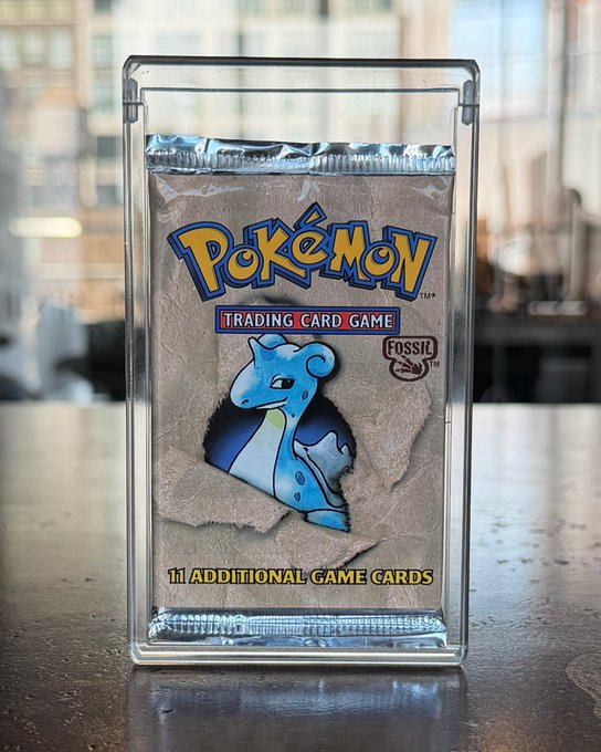 A sealed Pokémon Trading Card Game Fossil booster pack featuring Lapras artwork, encased in a protective plastic display case with the text '11 ADDITIONAL GAME CARDS.'