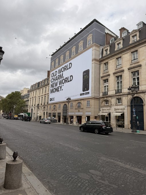 A street scene in Paris showing a large building billboard advertising BKFC with the slogan 'OLD WORLD CHARM. NEW WORLD MONEY.' alongside an image of a smartwatch.