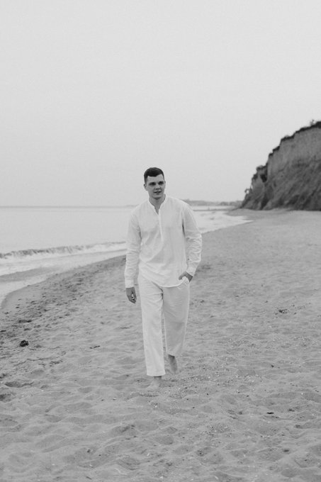 A man in white linen walks along a sandy beach, reflecting on his crypto journey since 2022, with his biggest wins including a 5-figure month and his bullishness on Pudgy Penguins and Abstract.
