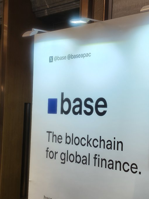 A promotional sign for 'base' with the tagline 'The blockchain for global finance.' and social media handles @base @baseapac, illuminated from above.