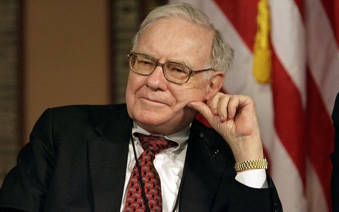 The image features a man sitting at a desk, wearing glasses and a suit jacket with a red necktie. He is smiling while looking off to the side. There are two words written on his tie that read "Warren Buffett" and "It'n't gonna do anything". These words are likely related to Bitcoin or cryptocurrencies in some context. The post also mentions how much Bitcoins are worth, which brings attention back to Warren Buffett's statement about them not being valuable.