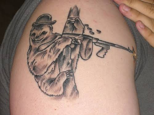 A black and grey tattoo on someone's skin depicts a sloth wearing a top hat and holding a rifle.