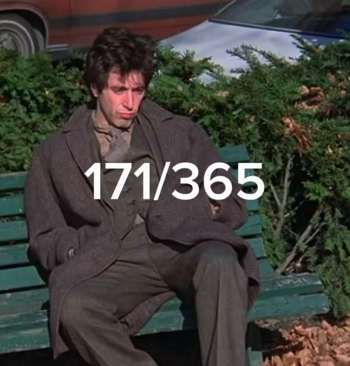 The image features a man sitting alone on a green park bench, wearing a brown coat and tie. There are leaves scattered around him, suggesting that he might be outside during autumn or winter. The text "XRP holders today" appears near the bottom of the image, which could possibly be related to Bitcoin or cryptocurrency news.