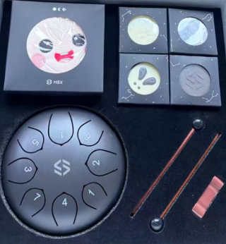 A collection of items including a box with a moon illustration, four circular coasters, a black lotus-shaped device, and two mallets on a dark surface.